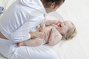 Mom changing diaper to the baby lying on his back