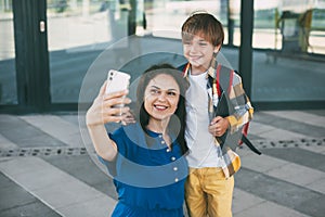Mom and child with a backpack take selfie on the phone before going to school or kindergarten. Happy parents and children. Back to