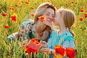 Mom with a child girl in a field of red poppies enjoys nature. Mother and little daughter in the poppy field. A young