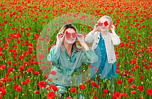 Mom with a child girl in a field of red poppies enjoys nature. Mother and little daughter in the poppy field. A young