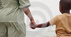 Mom, child and holding hands on beach for support, bonding and holiday with waves. Back of parent, mother or family with