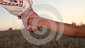 Mom and child holding hands together on wheat field sunset background. Son takes mother hand. Family, trust, love and