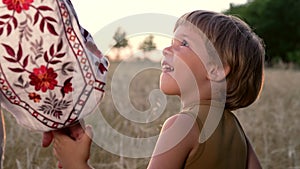 Mom and child holding hands together on wheat field sunset background. Son takes mother hand. Family, trust, love and