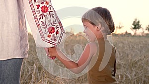 Mom and child holding hands together on wheat field sunset background. Son takes mother hand. Family, trust, love and