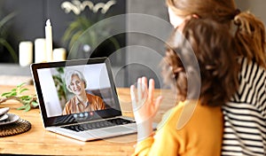 Mom and child making talking with grandma through video call on laptop