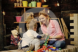 Mom and child play with details of constructor, plastic bricks. Nursery with chalkboard on background. Motherhood