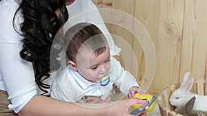 Mom with child playing smartphone, young mother using gadget with baby, easter rabbits in basket