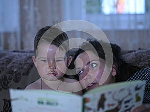Mom with a child read a book on the couch before going to bed