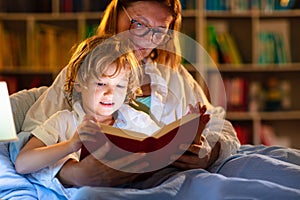 Mom and child reading book in bed. Kids read