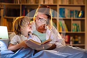 Mom and child reading book in bed. Kids read