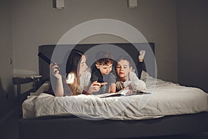 Mom and child reading a book with a flashlight