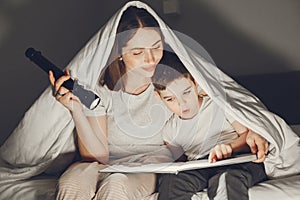 Mom and child reading a book with a flashlight