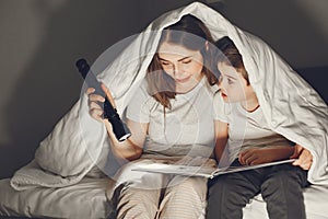 Mom and child reading a book with a flashlight