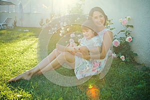 Mom and child smiling at blossoming rose flowers