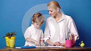 Mom and child spend time together. Family happiness concept. Mother teach son on blue background. Woman and little boy