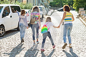 Mom and children holding hands walking around the city. Woman taking pictures at the camera, family tourism.