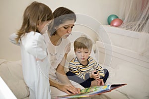 Mom with children reads a book before going to bed