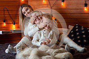 Mom with children in the winter frosty evening sitting on the bed and play together.