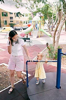 Mom circles the little girl on a turntable swing