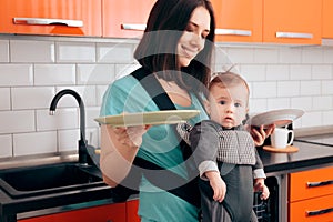 Mother Holding Dishes Holding  Baby in Carrier photo
