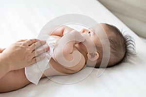 Mom cleaning up and wipe body baby by wet tissue when changing nappies or diaper and wiping the hands or face or leg, Personal photo