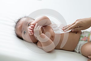 Mom cleaning up and wipe body baby by wet tissue when changing nappies photo