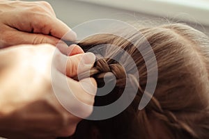 Mom is combing her daughter`s hair. Taking care of baby`s hair. The concept of a happy childhood and a good attitude towards