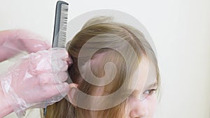 Mom combs daughter's hair and divides it into strands for highlighting.