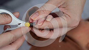 Mom cuts her newborn son's fingernails with small children's scissors.