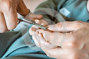 Mom cuts newborn baby nails with scissors. Female hands and hands of newborn baby close up. Children manicure