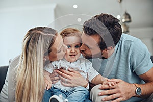 Mom, dad and baby kiss on sofa in living room of happy family home, young parents and child together. Love, happiness