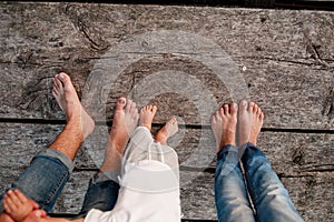 Mom, dad and baby walk bare feet on the wooden bridge. Happy young family spending time together, running outside, go in nature,