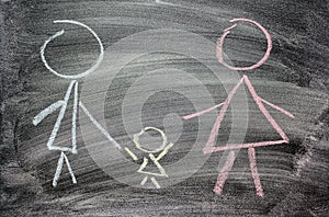 Mom, dad and child drawn in chalk on black slate as symbol of family love