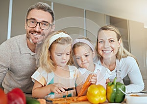 Mom, dad and children in the kitchen, cooking together and learning. Portrait of family at home teaching kids how to