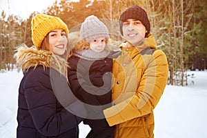 Mom and dad are cuddling and kissing their little son in winter park.