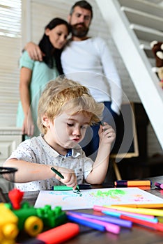 Mom and dad drawing with child. Happy family of three having fun together. Cheerful parents playing with son. Father