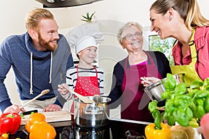 Mom, dad, granny and grandson together in kitchen preparing food