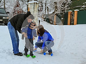 Mom and dad help their son put on skis. Winter entertainment of russian children.