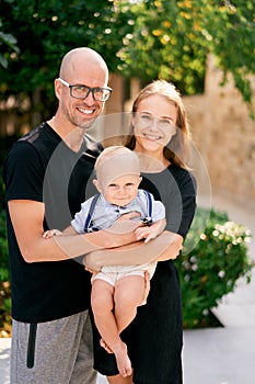 Mom and dad hugging holding a little boy