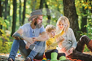 Mom dad and kid boy relaxing while hiking in forest. Family picnic. Mother father and little son sit forest picnic. Good