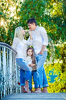 Mom, Dad and kid laughing hugging, enjoying nature