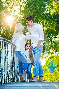 Mom, Dad and kid laughing hugging, enjoying nature