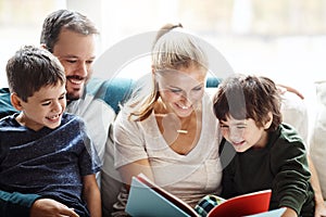 Mom, dad and kids reading books on sofa for storytelling time with smile in happy family home. Love, learning and couple