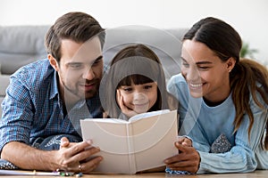 Mom and dad with little cute daughter reading book together