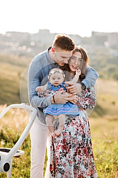 Mom, dad and little girl having fun outdoors in the grass on summer day. mother`s, father`s and baby`s day. Happy family for a