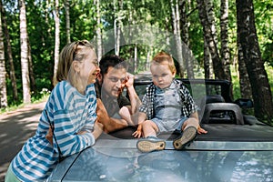 Mom, dad and little son in a convertible car. Summer family road trip to nature