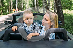 Mom, dad and little son in a convertible car. Summer family road trip to nature