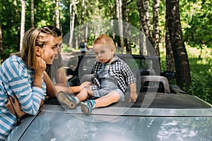 Mom, dad and little son in a convertible car. Summer family road trip to nature