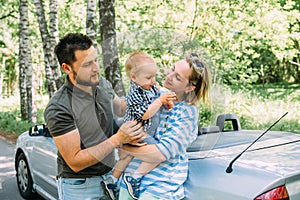 Mom, dad and little son in a convertible car. Summer family road trip to nature