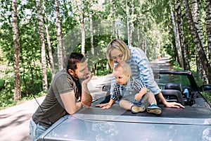 Mom, dad and little son in a convertible car. Summer family road trip to nature